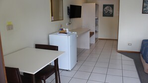 A compact kitchen with a refrigerator, a microwave, and a sink. There is a dining table with chairs and a small counter with a sink. - Dunolly Golden Triangle Motel (Dunolly)
