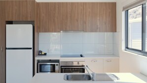 A modern kitchen with wooden cabinets, a white countertop, a stainless steel sink, and a window providing natural light. - Discovery Parks - Alice Springs (Ross)