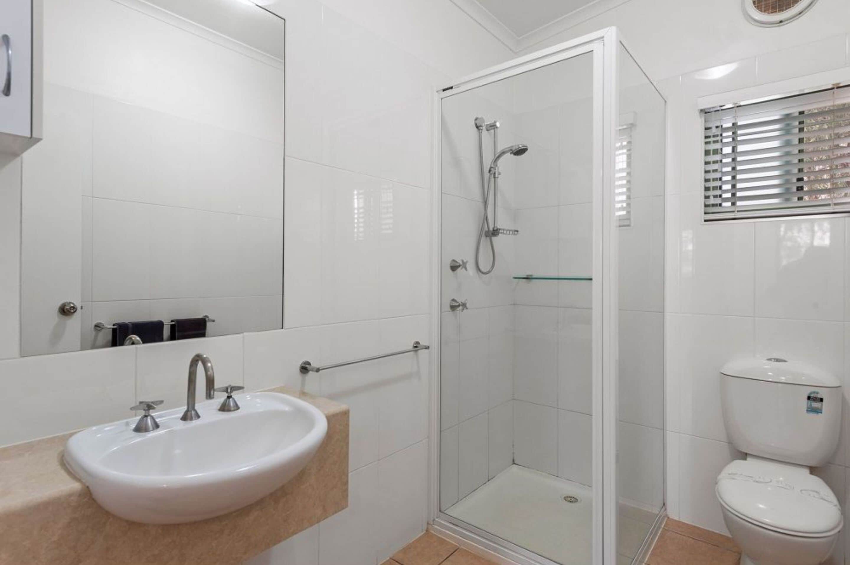 A bathroom with a white sink, a glass shower enclosure, and a toilet.