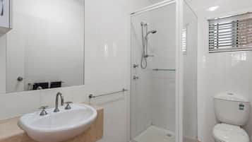 A bathroom with a white sink, a glass shower enclosure, and a toilet.