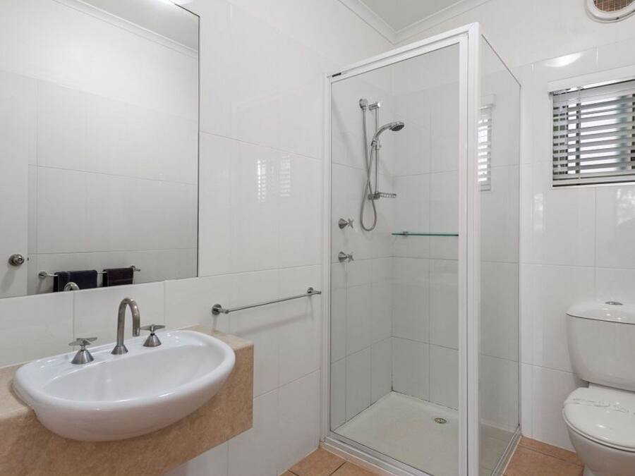 A bathroom with a white sink, a glass shower enclosure, and a toilet.