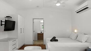 A modern hotel room with a bed, a desk, a chair, a television, and a ceiling fan.
