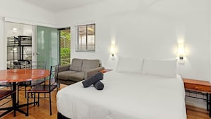 A bedroom with a bed, a sofa, a dining table, and a chair. - Discovery Parks - Alice Springs (Ross)