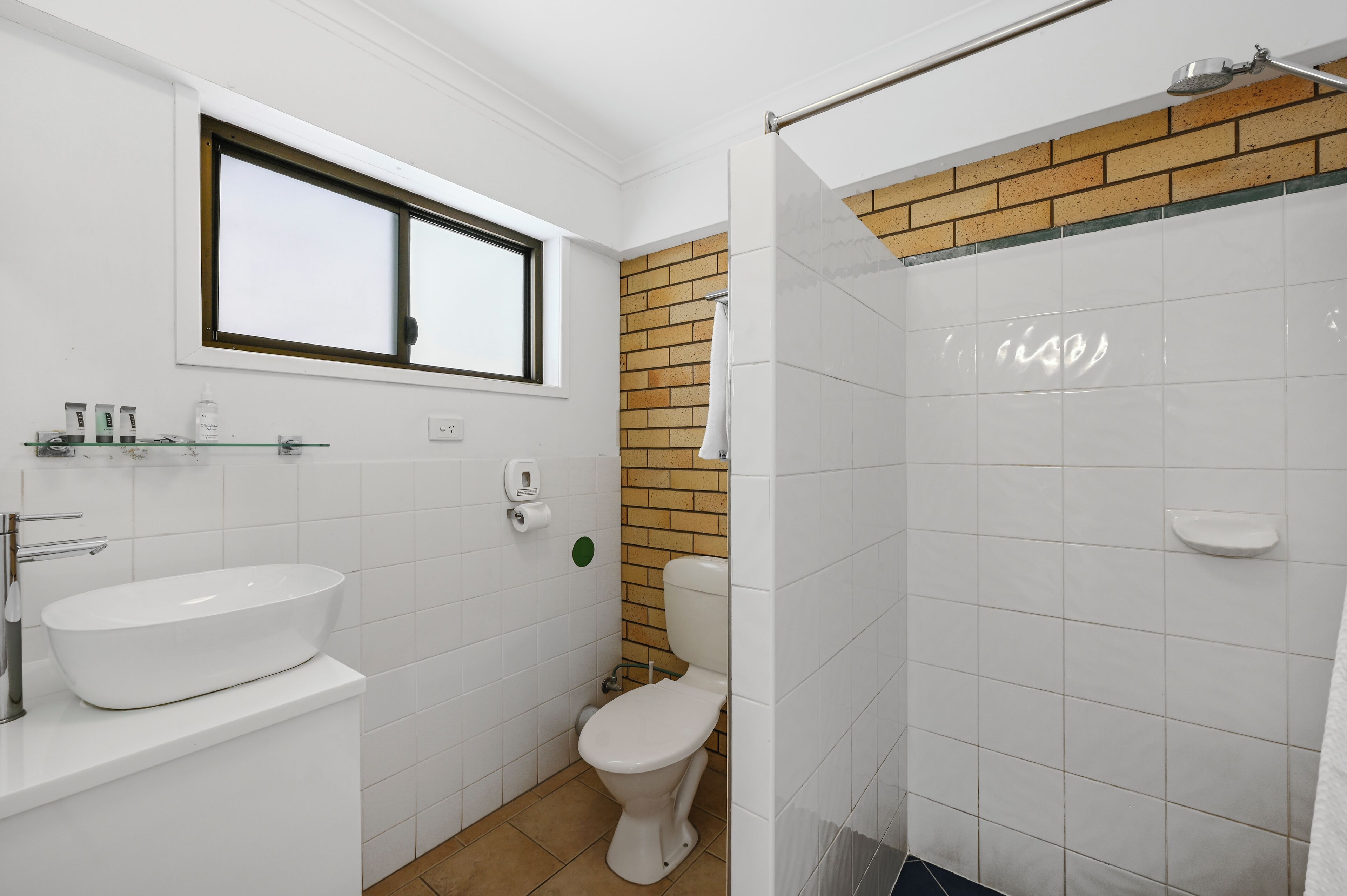 Un baño con lavamanos blanco, inodoro y zona de ducha.