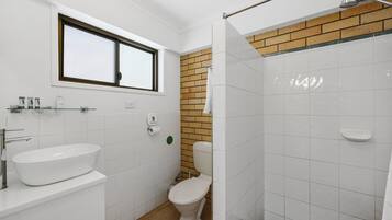 Un baño con lavamanos blanco, inodoro y zona de ducha.