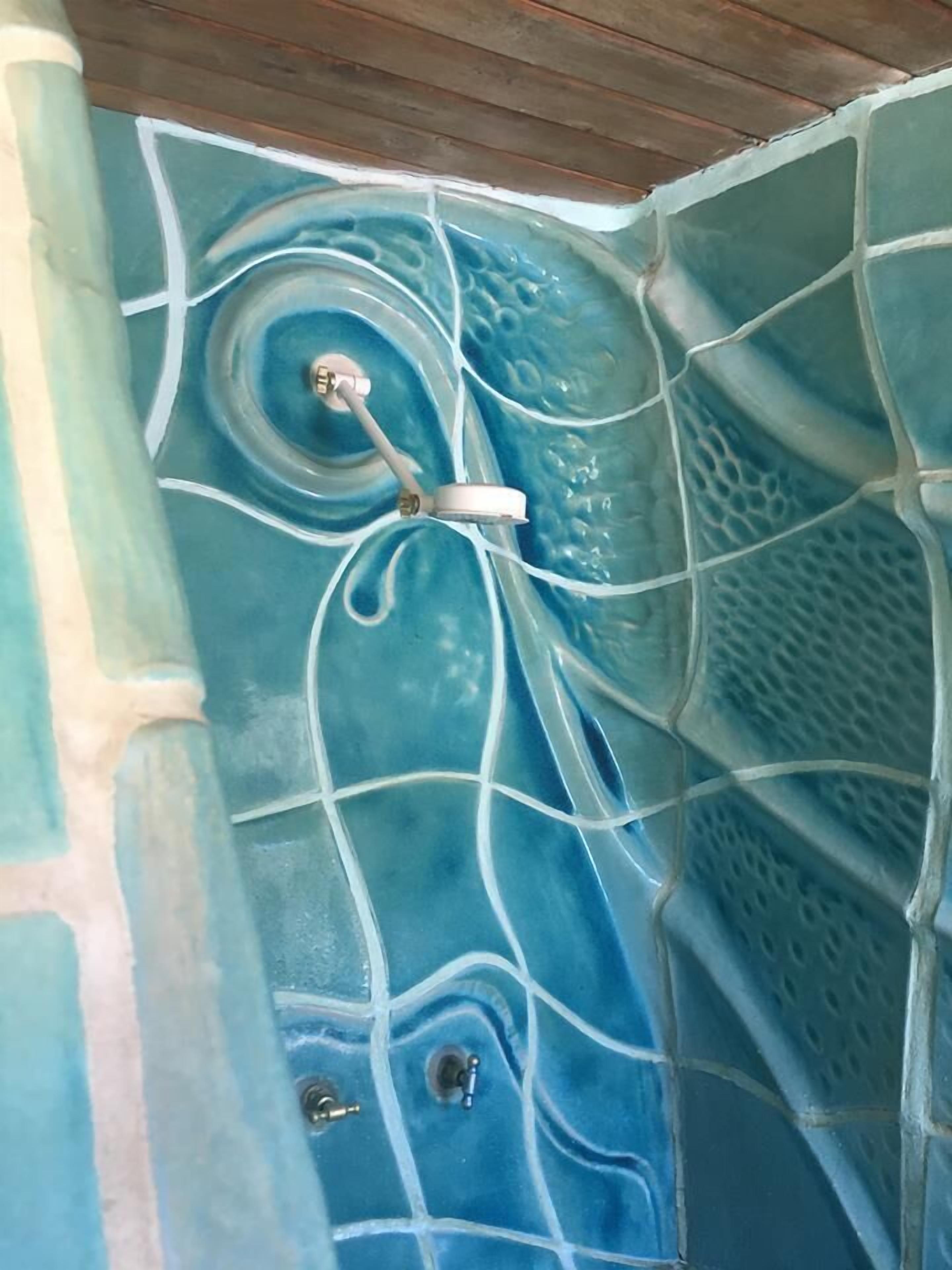 A bathroom with a mosaic tile wall featuring a blue and white abstract design.