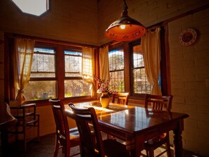 A dining area with a wooden table, chairs, a vase with flowers, and a clock on the wall. - Barkala Farmstay (Dandry)