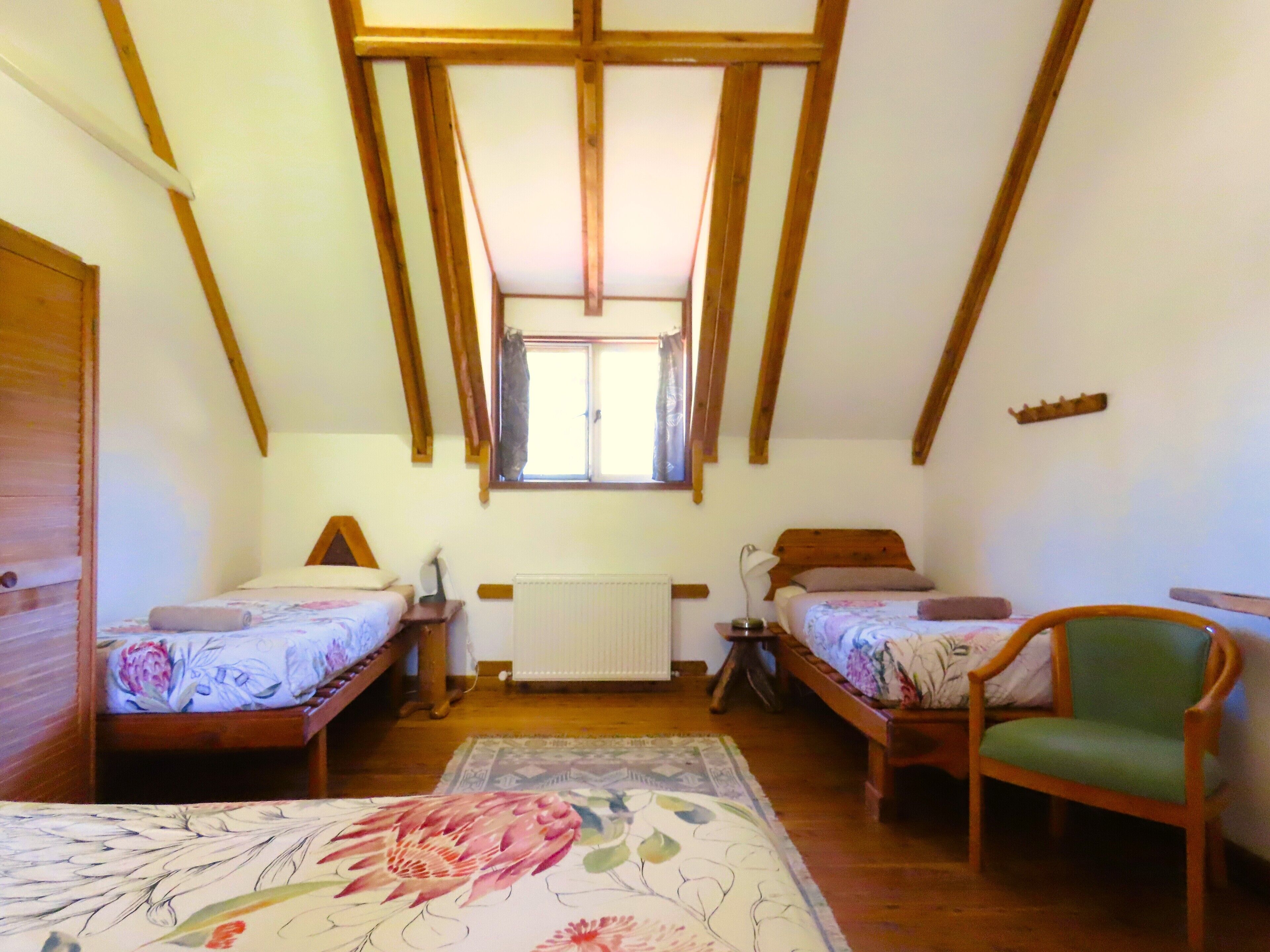A room with two beds, a radiator, a window, and a chair.