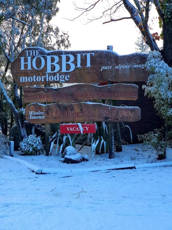 A wooden sign with multiple text elements advertising a motor lodge, luxury, and wireless internet availability.