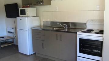 A compact kitchen with a refrigerator, microwave, stove, and sink.