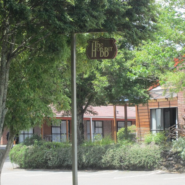 Un letrero que dice "The Hobbit", un edificio con fachada de ladrillo y un árbol en primer plano.
