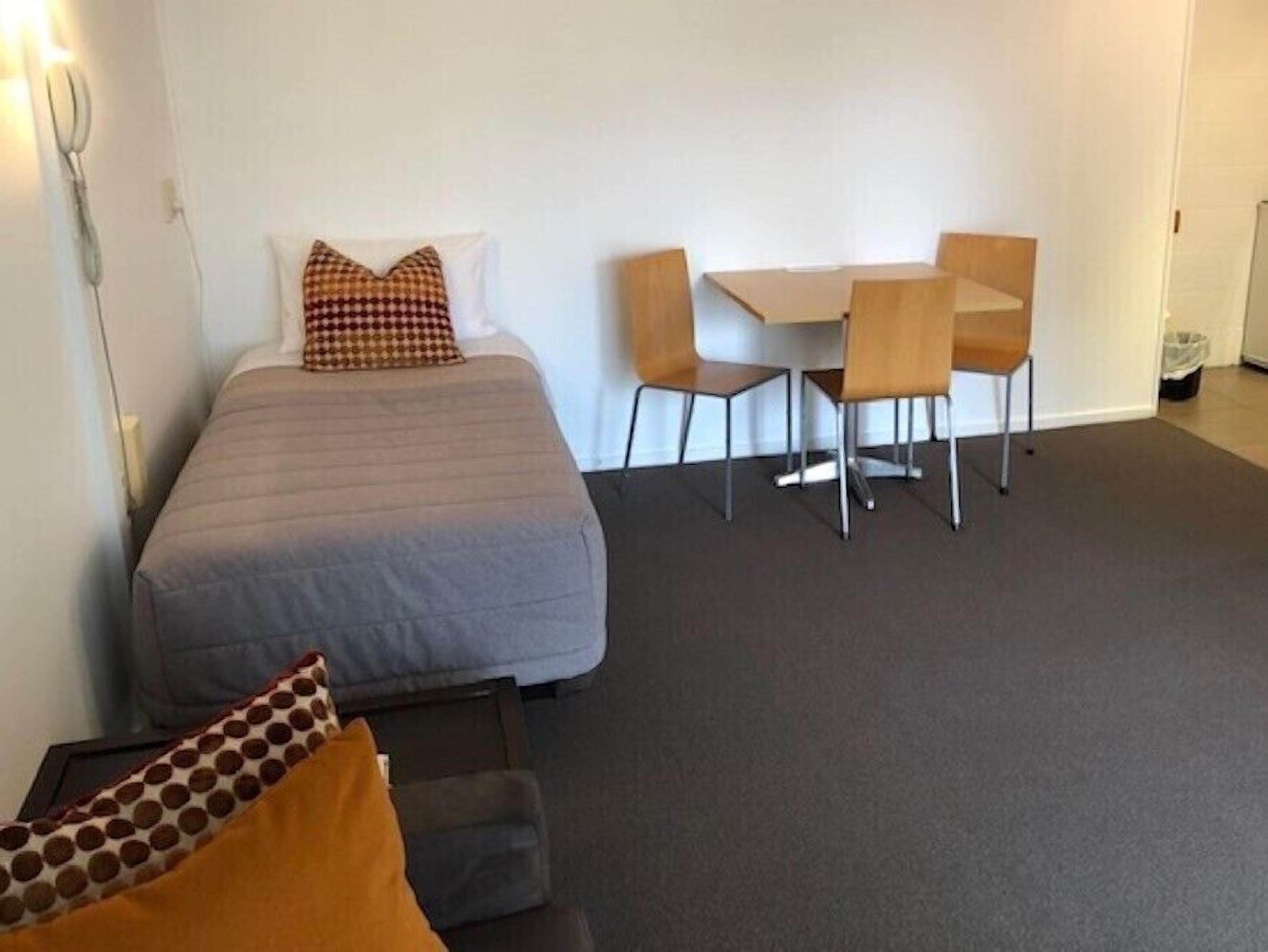 A bedroom with a bed, a desk, and two chairs.