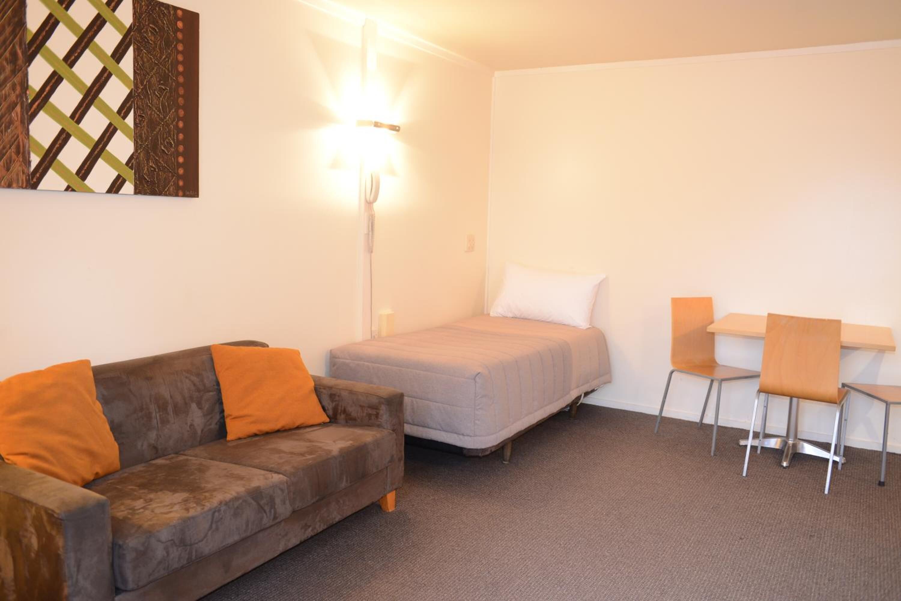 A room with a sofa, a bed, and a desk with chairs.