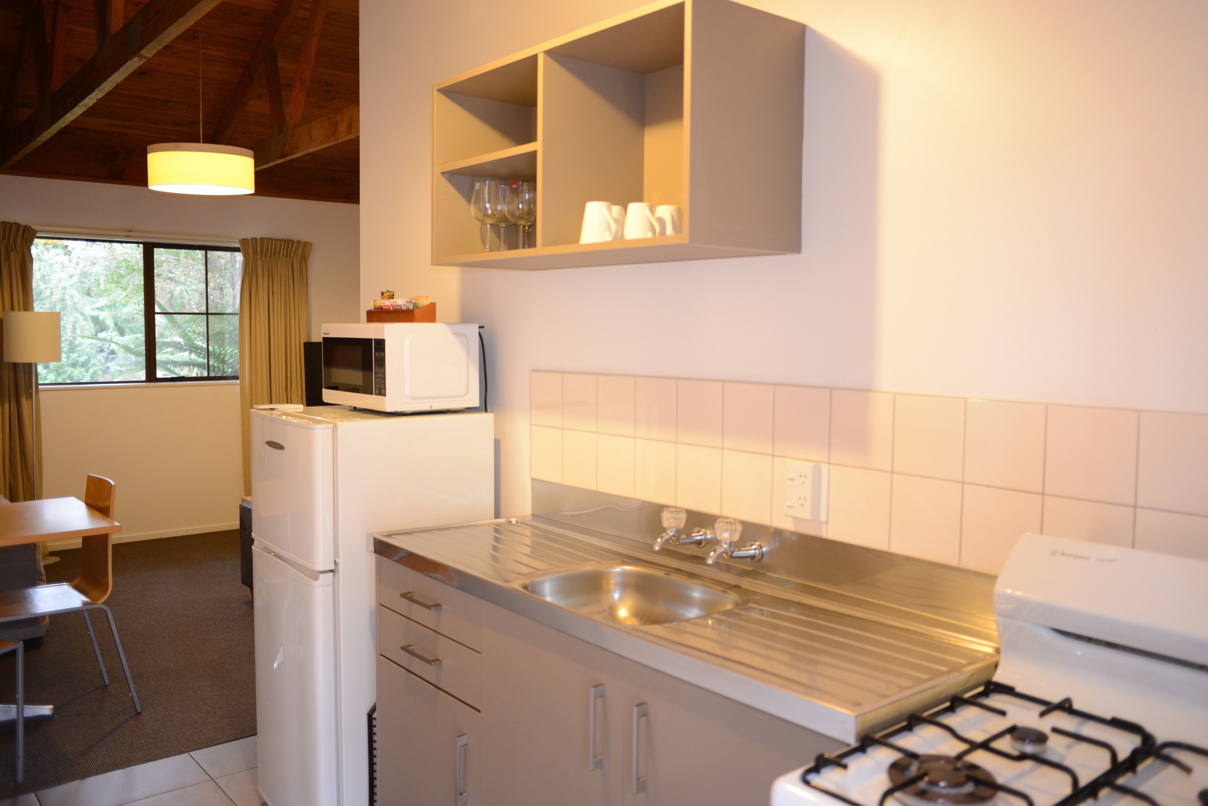 Cocina compacta con refrigerador, microondas, pileta y estufa.