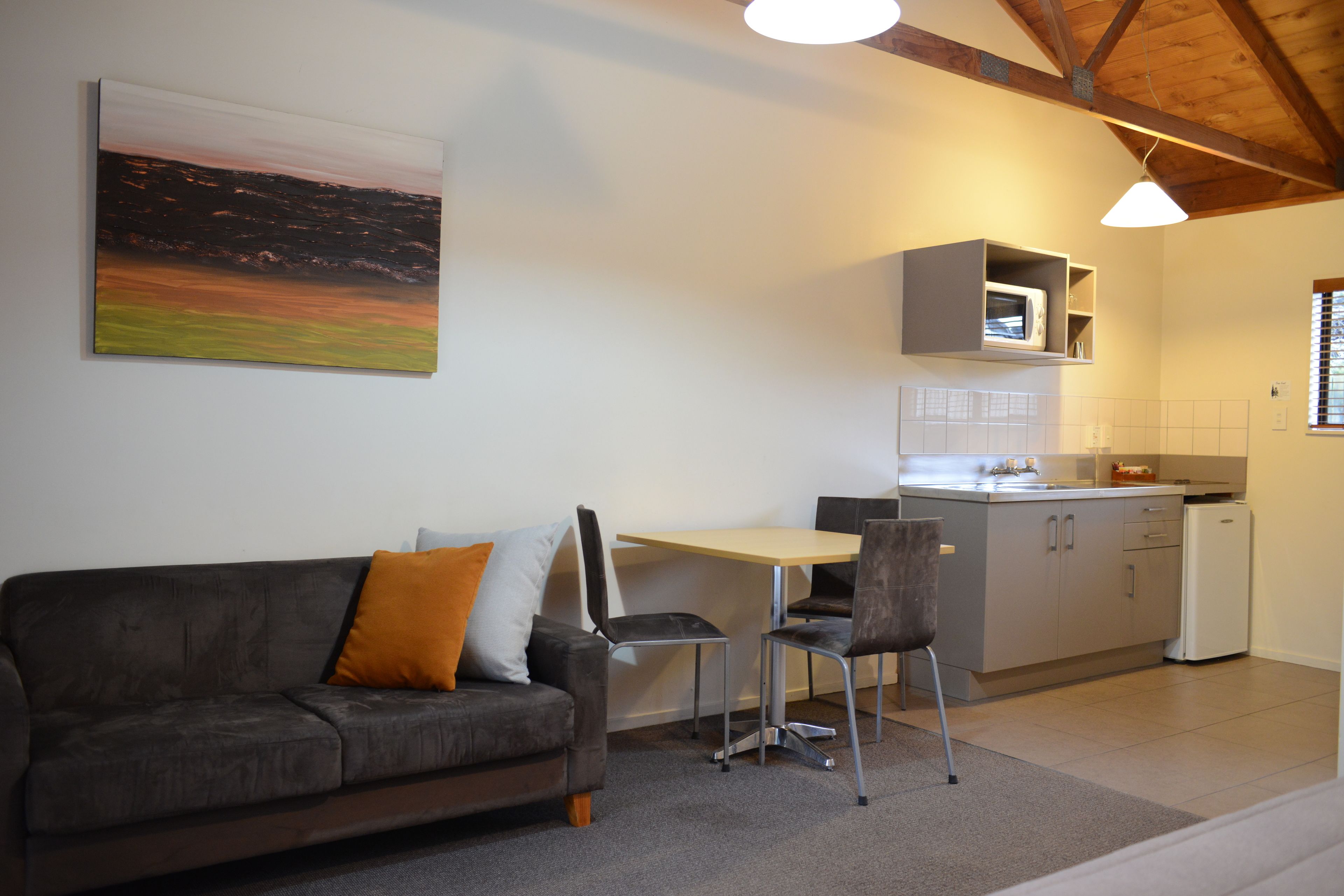 Un espace de vie moderne comprenant un canapé, des fauteuils, une table à manger et un coin cuisine.