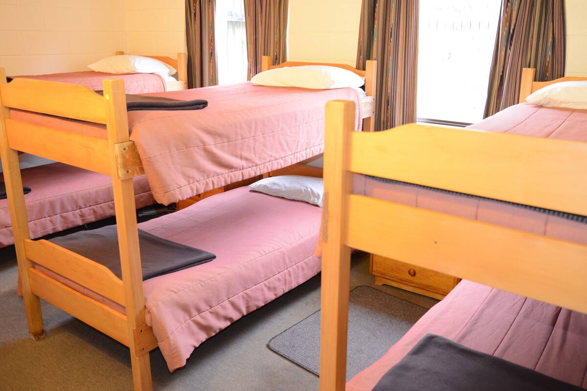 Un dormitorio con literas, cabeceros de madera y una ventana con cortinas.