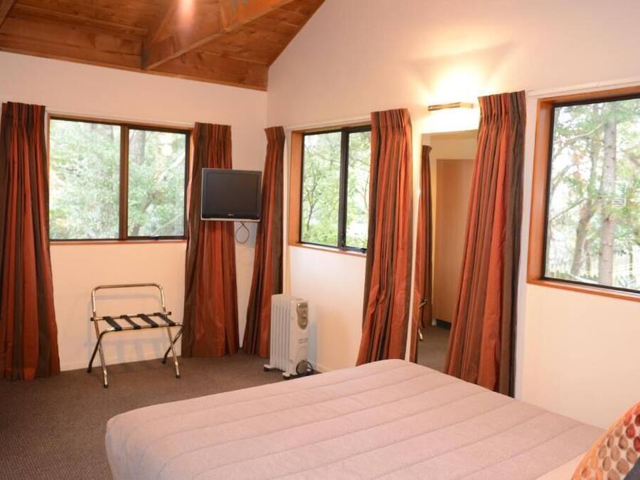 Ein Schlafzimmer mit Bett, Fernseher, Heizkörper und Vorhängen.