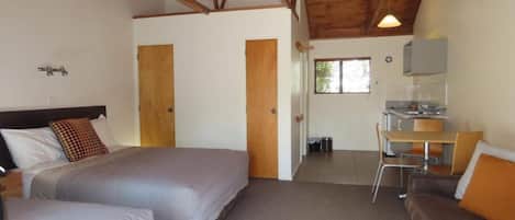 A room with two beds, a small kitchenette, and a dining area.