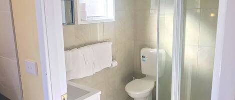 A small, clean bathroom with a toilet, a towel rack, and a window.