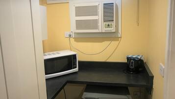 A compact kitchenette with a microwave, a coffee maker, and a small refrigerator.