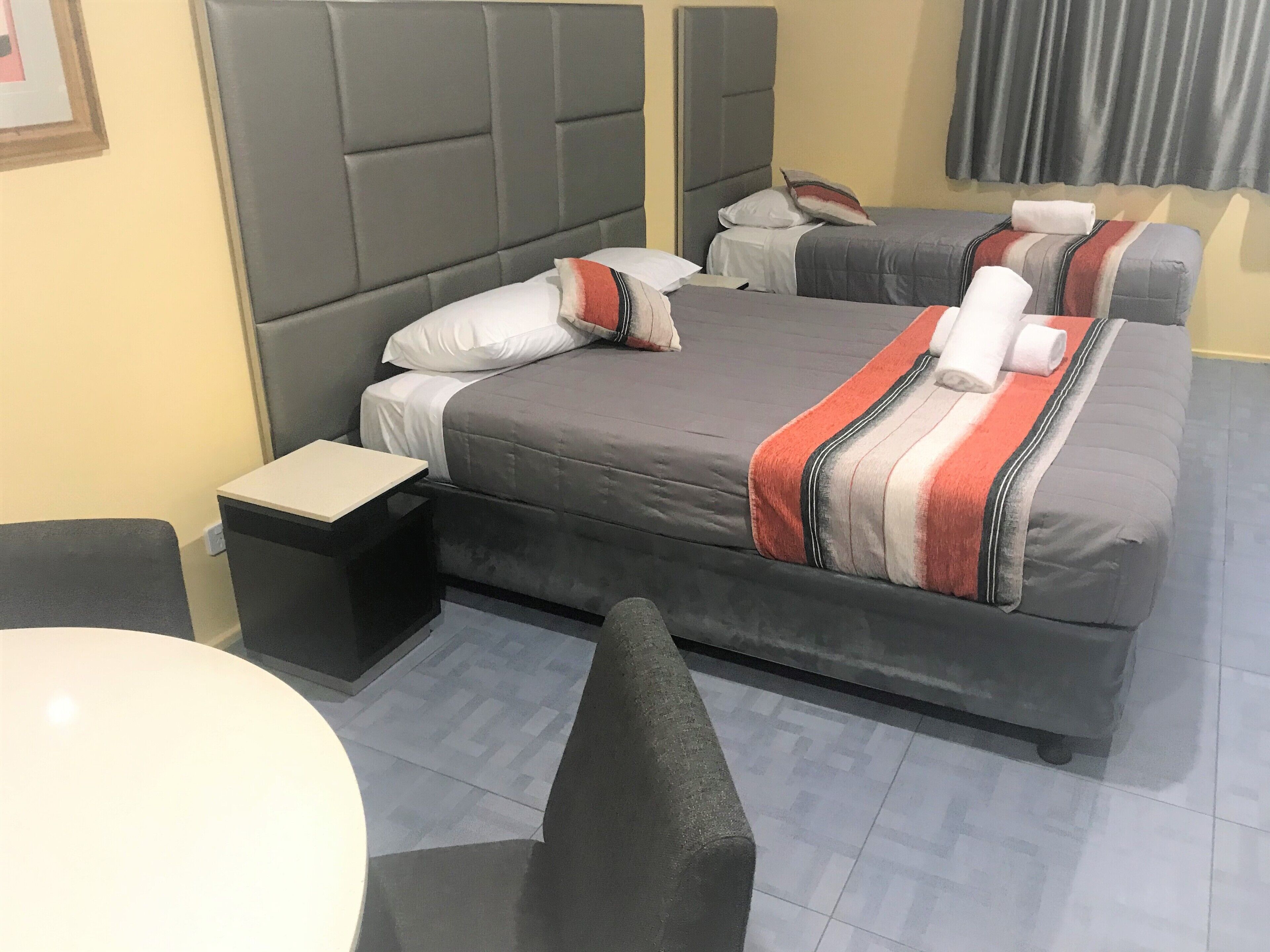 A hotel room with a large bed, a bedside table, and a chair.
