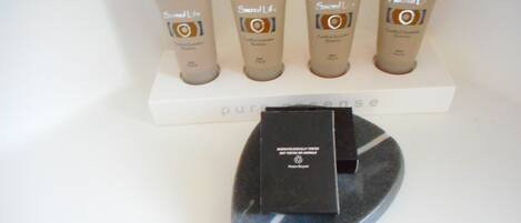 A display of four body care products on a white shelf with a black box below.