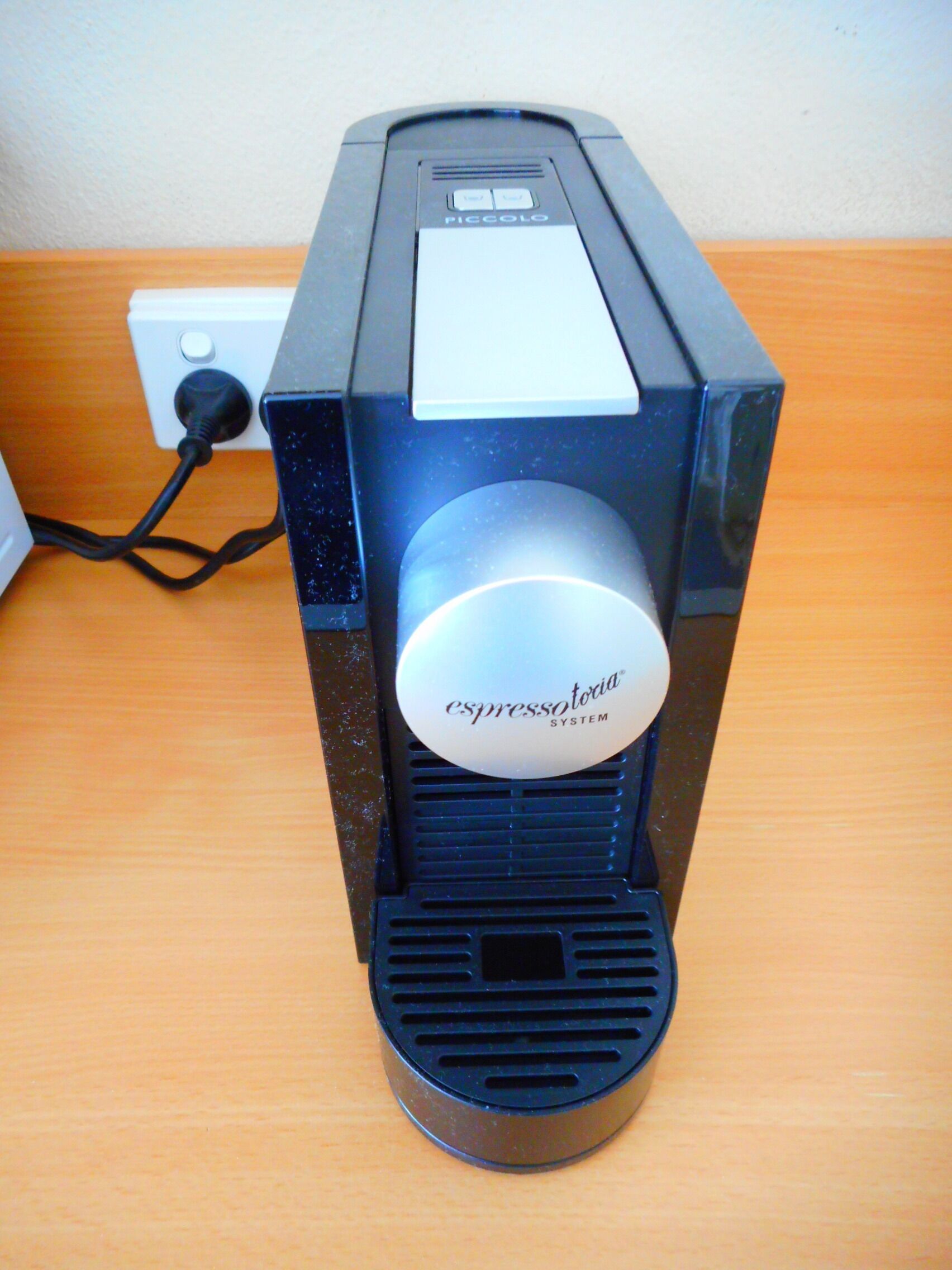 A coffee machine with a control panel and a power cord plugged in.