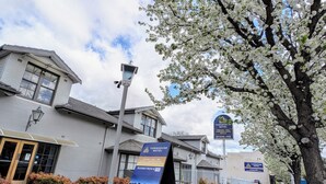 Et townhouse motel med et skilt, der reklamerer for gratis WiFi, pool, grill, Netflix, erhvervspriser, gruppereservationer og selskaber.
