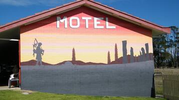 A motel with a mural of a person holding a rifle and a sunset.