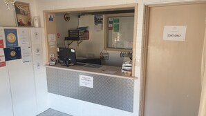 Ein Empfangsschalter mit einem Computer, einem Schild mit der Aufschrift 'Nur für Mitarbeiter' und verschiedenen Auszeichnungen und Aushängen an der Wand.