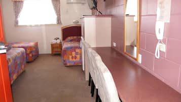 A compact room with two beds, a small table, a mirror, and a telephone.