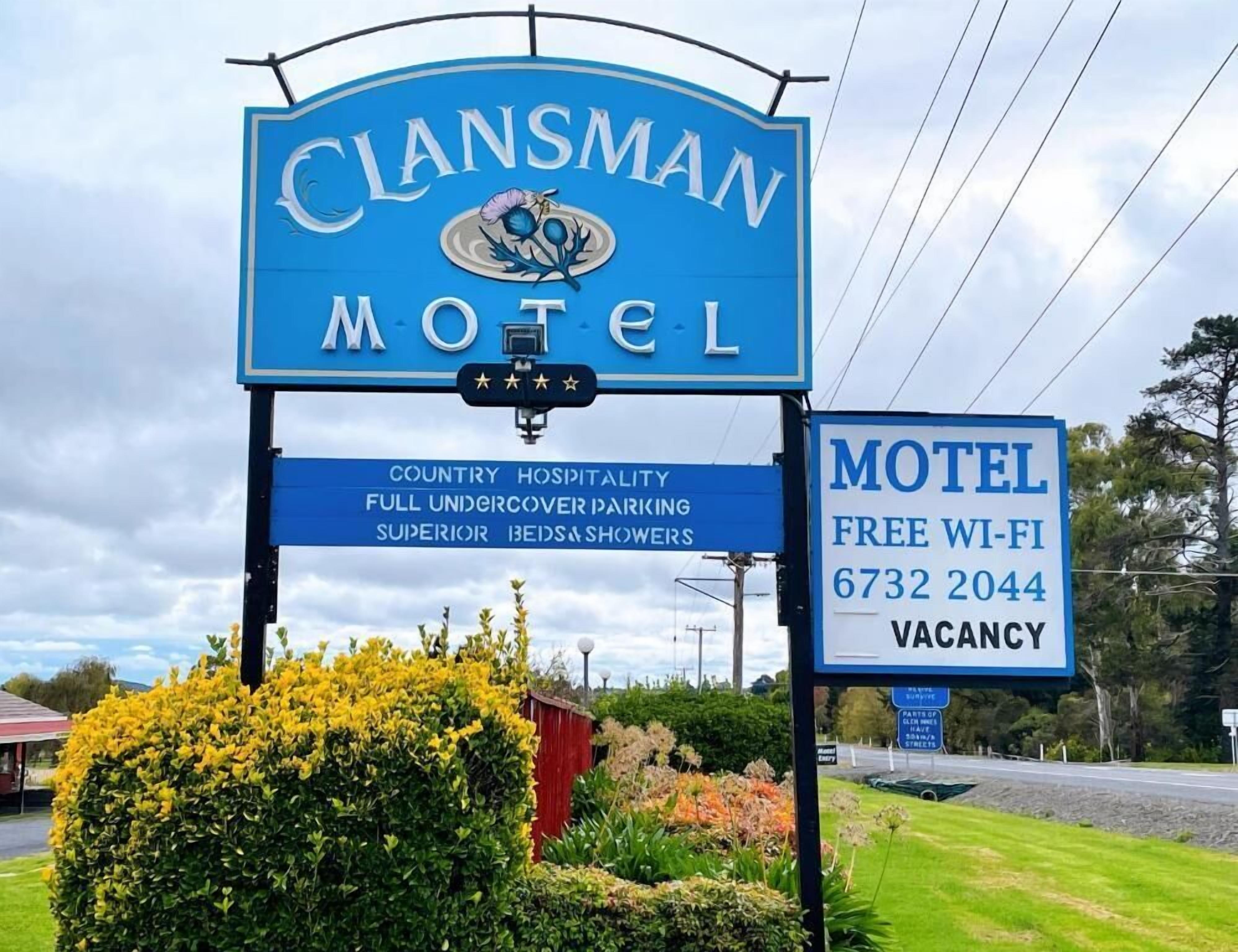 Cartello di un motel con il nome 'Clansman Motel' e servizi indicati come ospitalità rurale, parcheggio coperto completo, biancheria da letto di qualità superiore e docce.