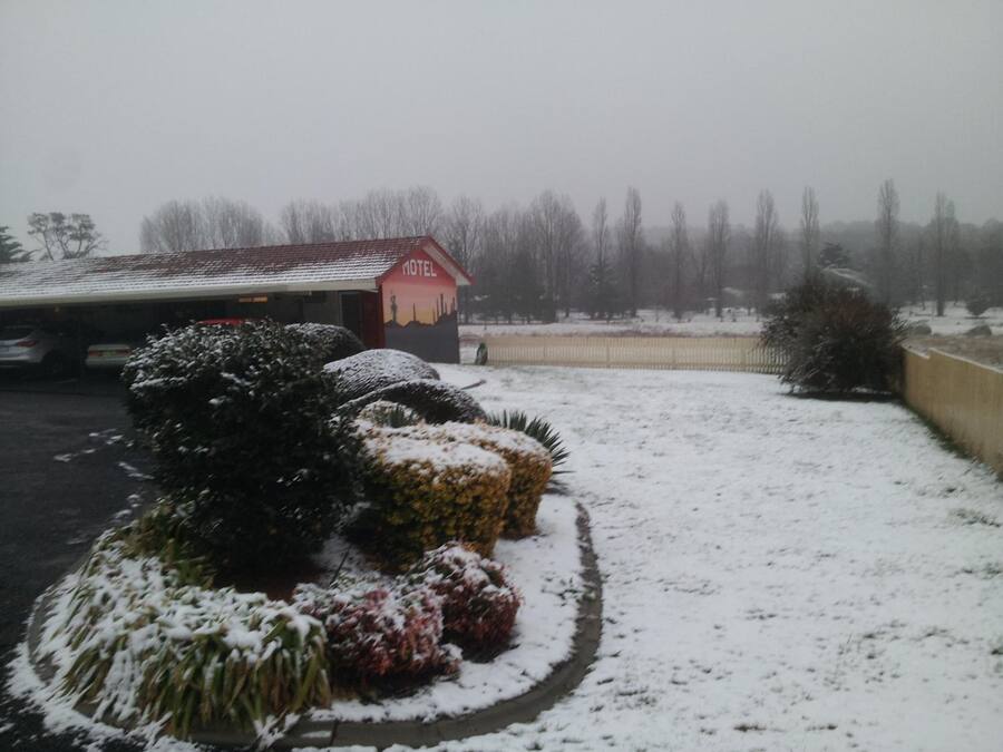 A snow-covered landscape with a motel building in the background.