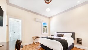 A bedroom with a bed, a desk, a chair, a window, and a door. - Canungra Hotel (Canungra)