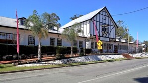 A historic building with a prominent corner entrance, a stone facade, and a flagpole. - Canungra Hotel (Canungra)