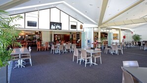A spacious dining area with high ceilings and natural light, featuring multiple dining tables and chairs, and a television mounted on the wall. - Canungra Hotel (Canungra)