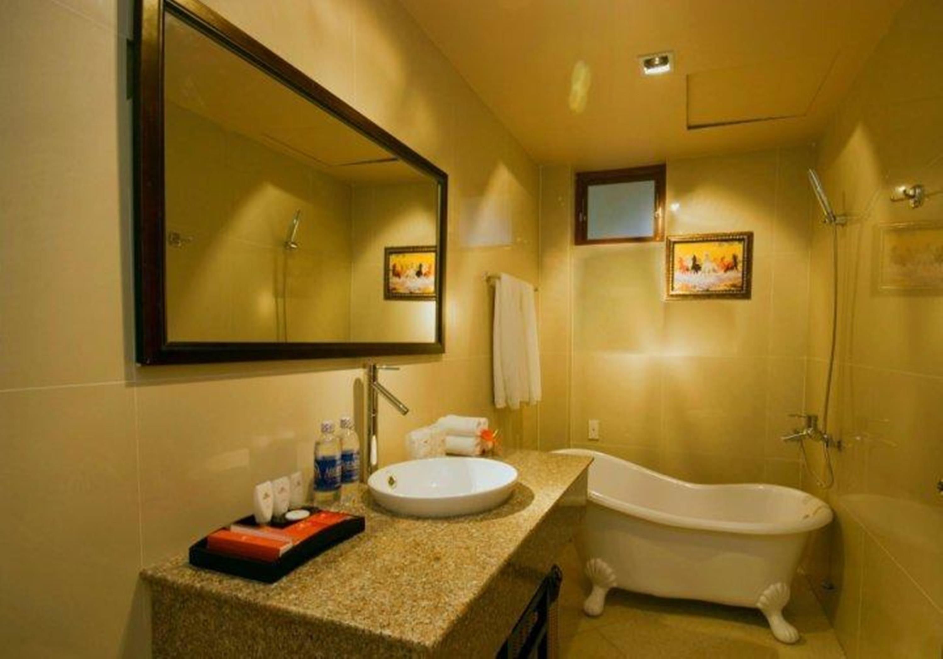 A bathroom with a freestanding bathtub, a sink, and a large mirror.