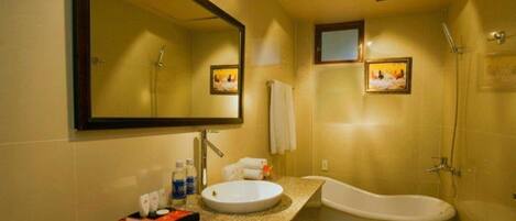 A bathroom with a freestanding bathtub, a sink, and a large mirror.