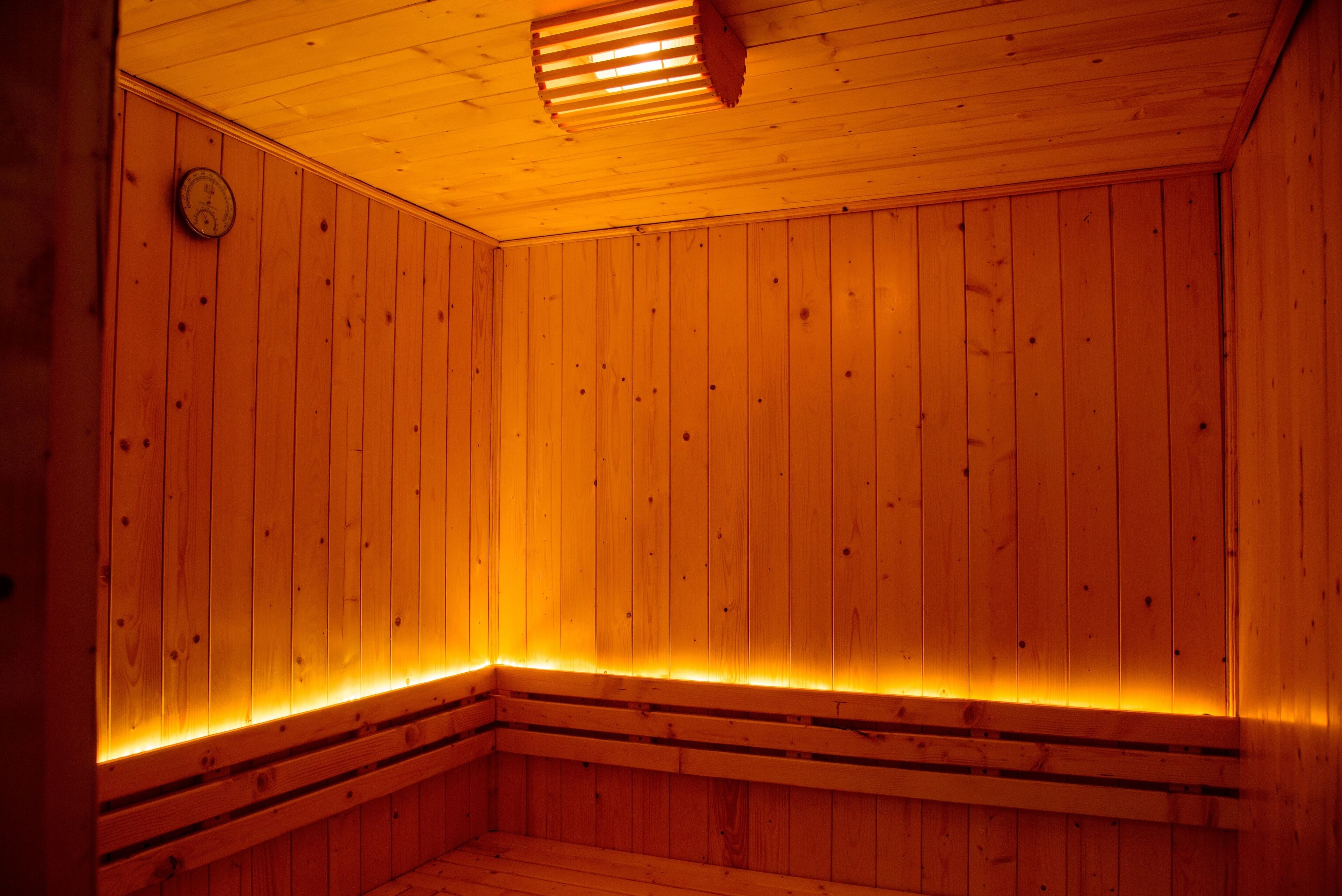 A wooden sauna with a sloped ceiling and a clock on the wall.