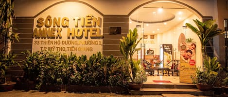 The exterior of Sông Tien Annex Hotel with a signboard, potted plants, and a well-lit entrance.