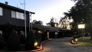 Un motel con camino de grava, un cartel que indica el nombre del motel y un césped bien cuidado.