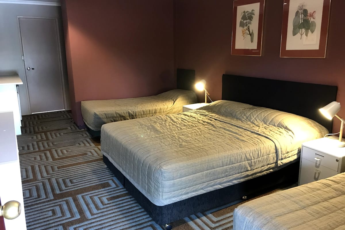 A hotel room with two beds, a desk, and a nightstand with lamps.