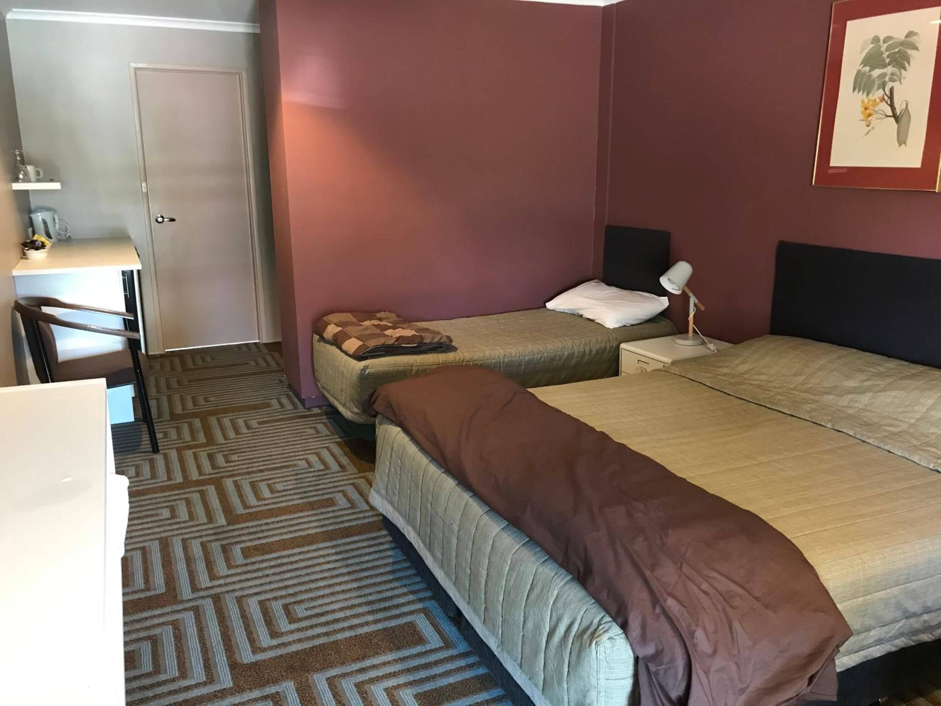 A hotel room with two beds, a desk, and a chair.