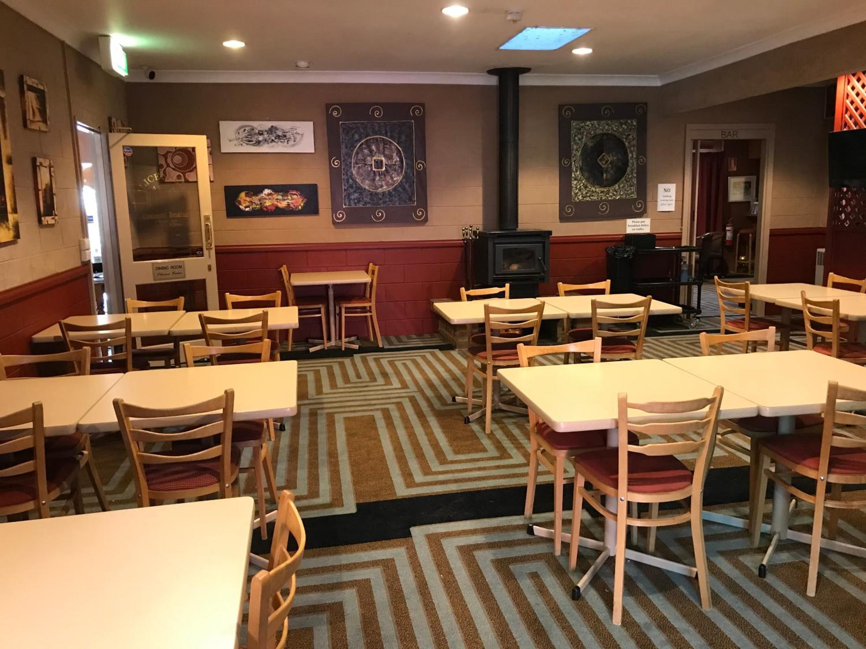 A dining room with tables and chairs, a fireplace, and artwork on the walls.