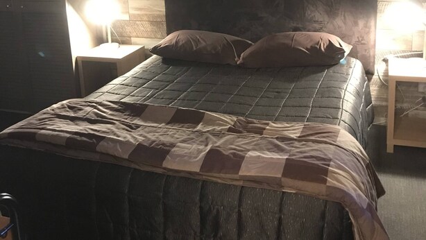 Un dormitorio con una cama, dos mesitas de noche, una obra de arte colgada en la pared y un panel de madera.