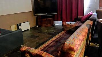 Un salon avec un canapé, un téléviseur et un tapis à motifs.