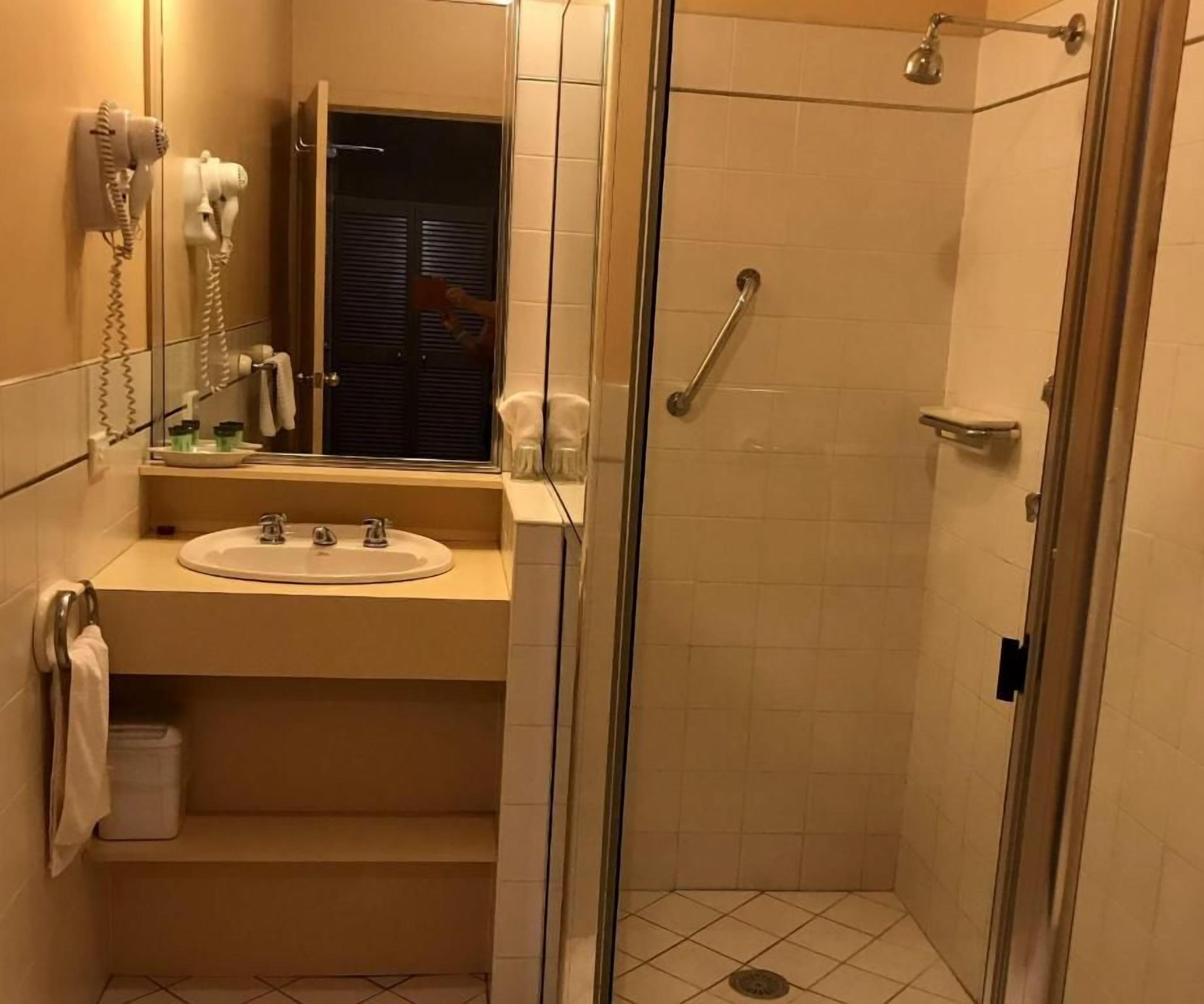 A bathroom with a sink, mirror, and a glass-enclosed shower area.