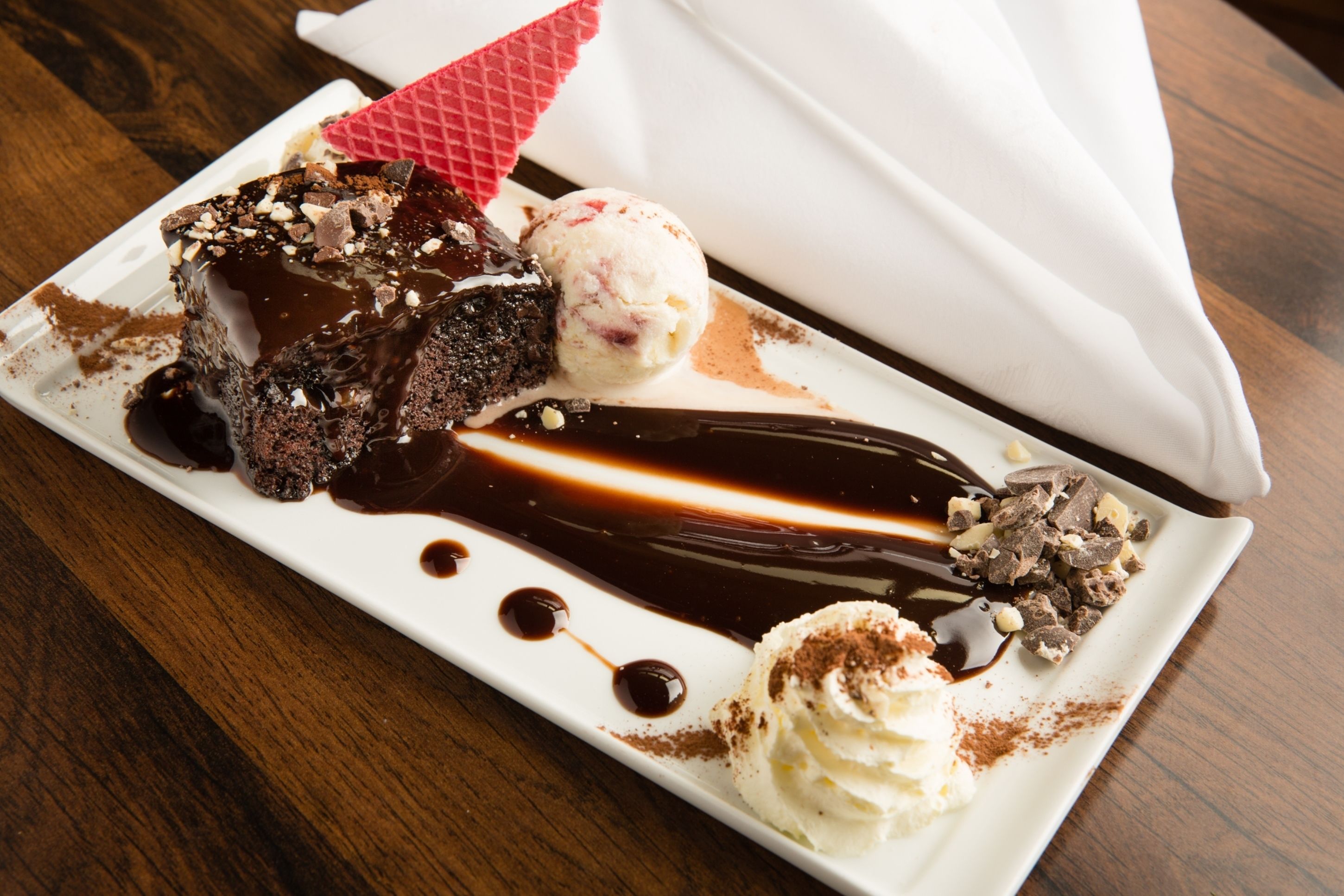 Une assiette de dessert avec un gâteau au chocolat, de la glace et de la crème fouettée.