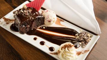 Une assiette de dessert avec un gâteau au chocolat, de la glace et de la crème fouettée.