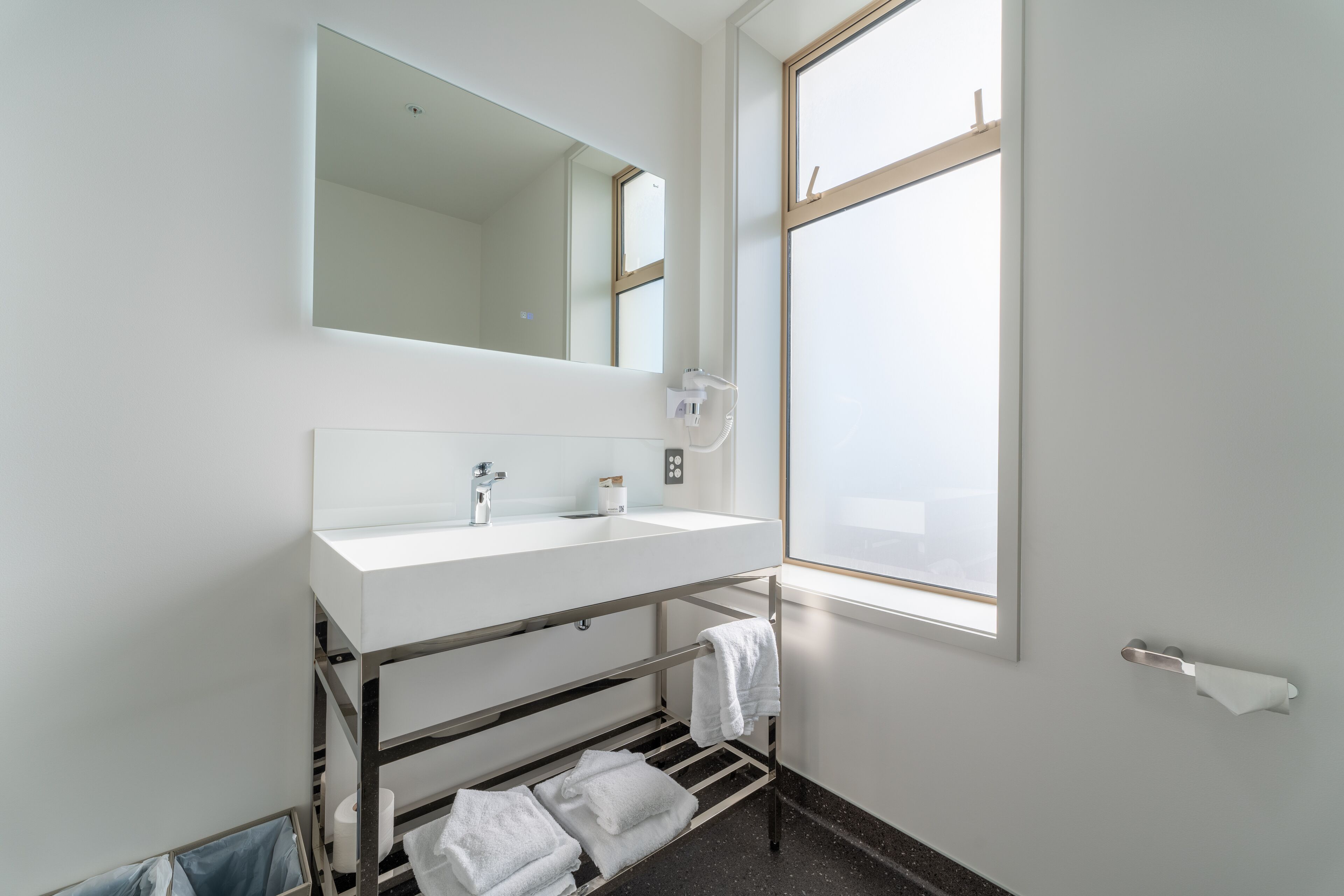 Een moderne badkamer met een wit wastafelmeubel, spiegel en handdoekhouder.